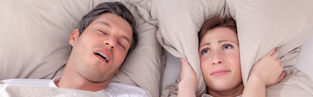 man snoring in bed with wife