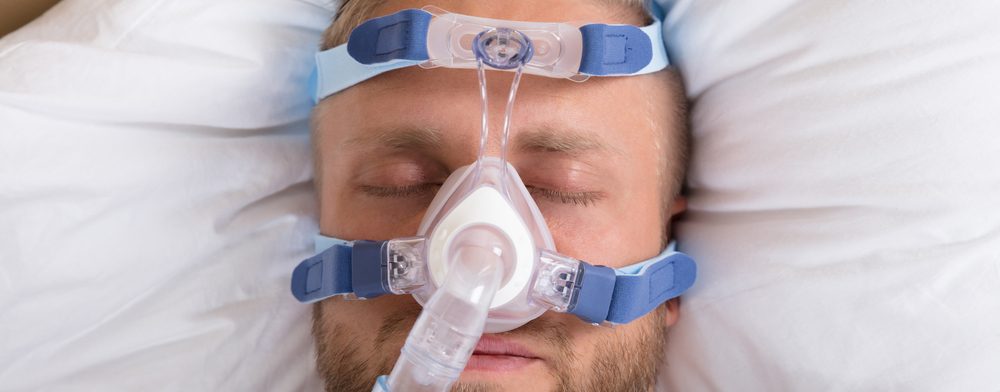 man wearing cpap machine in bed