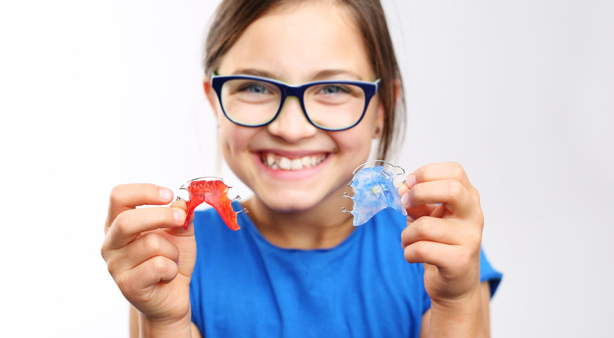 adolescent girl with retainer in hand