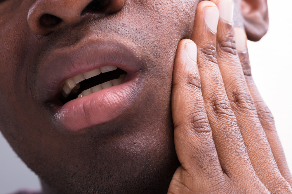 African-American man holding face from jaw pain