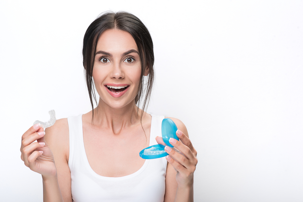 smiling young woman holding her Invisalign case