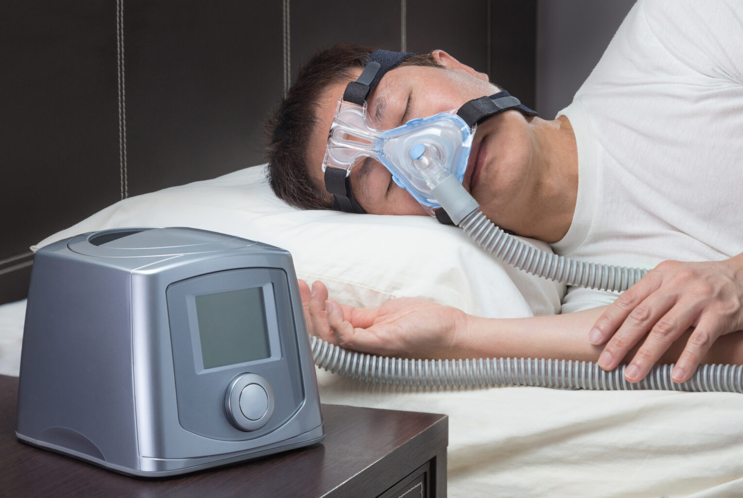 Asian man with sleep apnea using CPAP machine