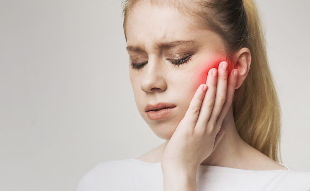 young woman touching face because of jaw pain on white background