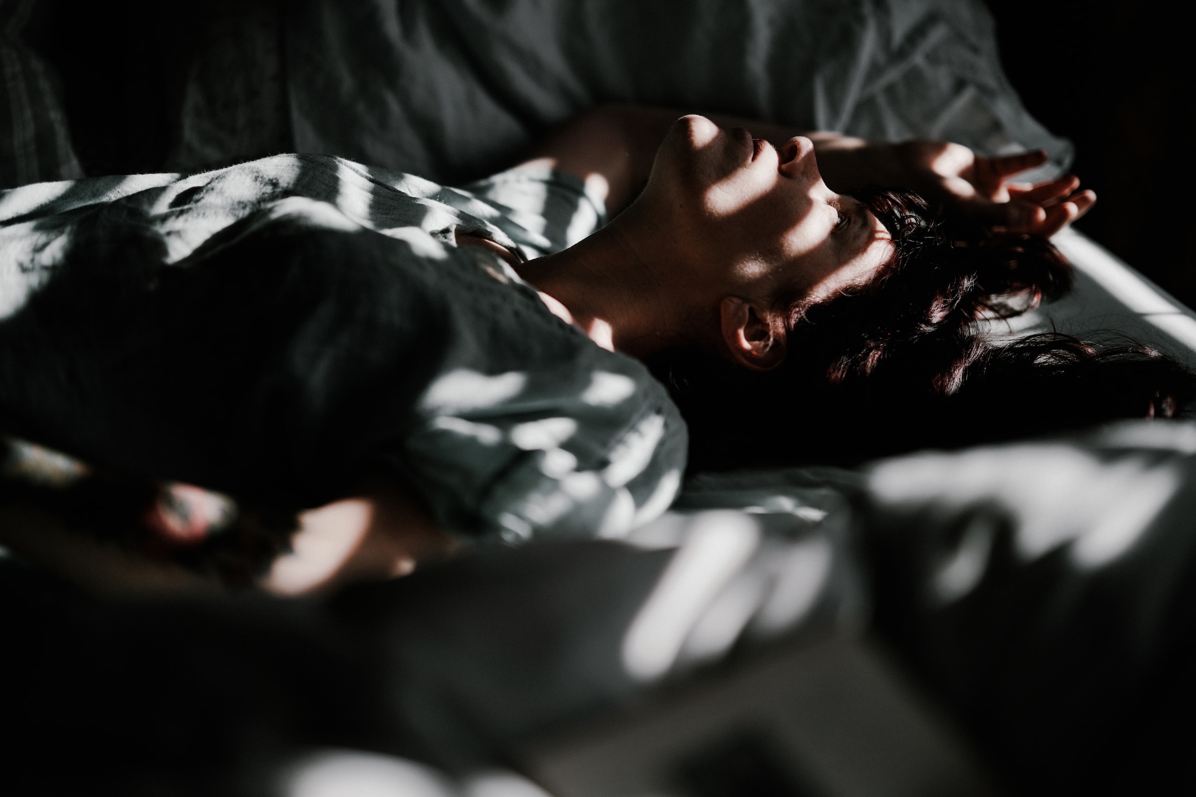 Man lying on the bed with light shining through the blinds