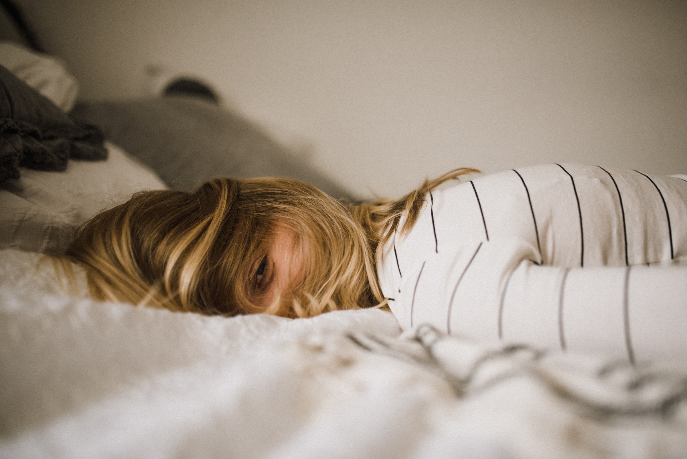 Woman in a striped shirt lying on the bed