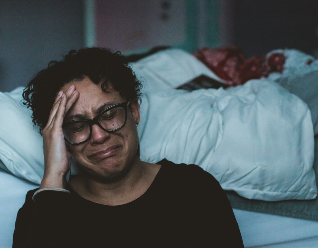woman crying and sitting on the side of her bed