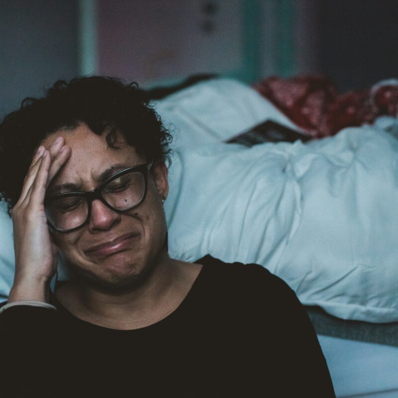 woman crying and sitting on the side of her bed