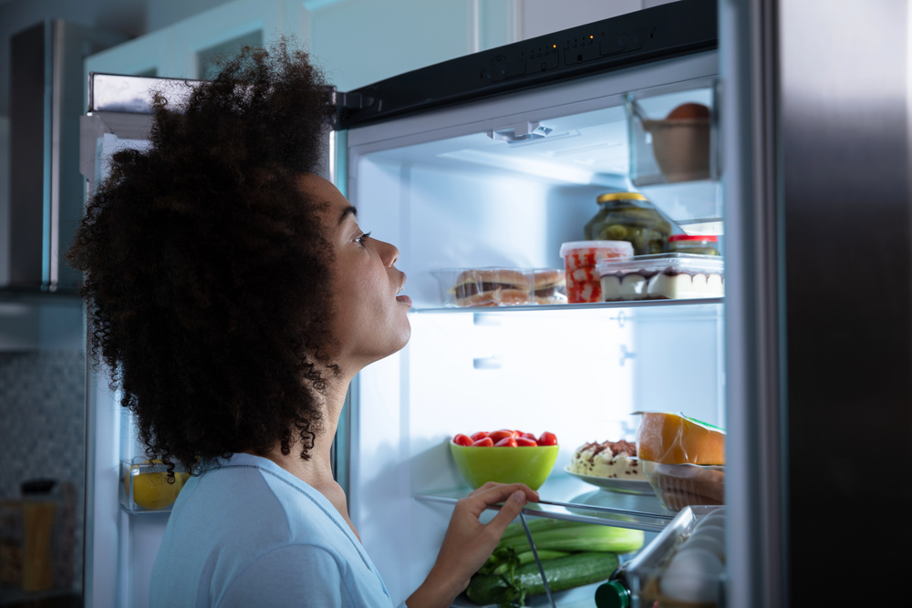 black woman with sleep apnea looking in fridge for a late night snack