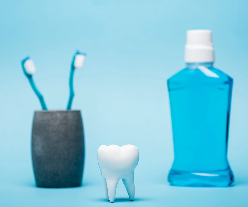 tooth, toothbrushes, and mouthwash on blue background