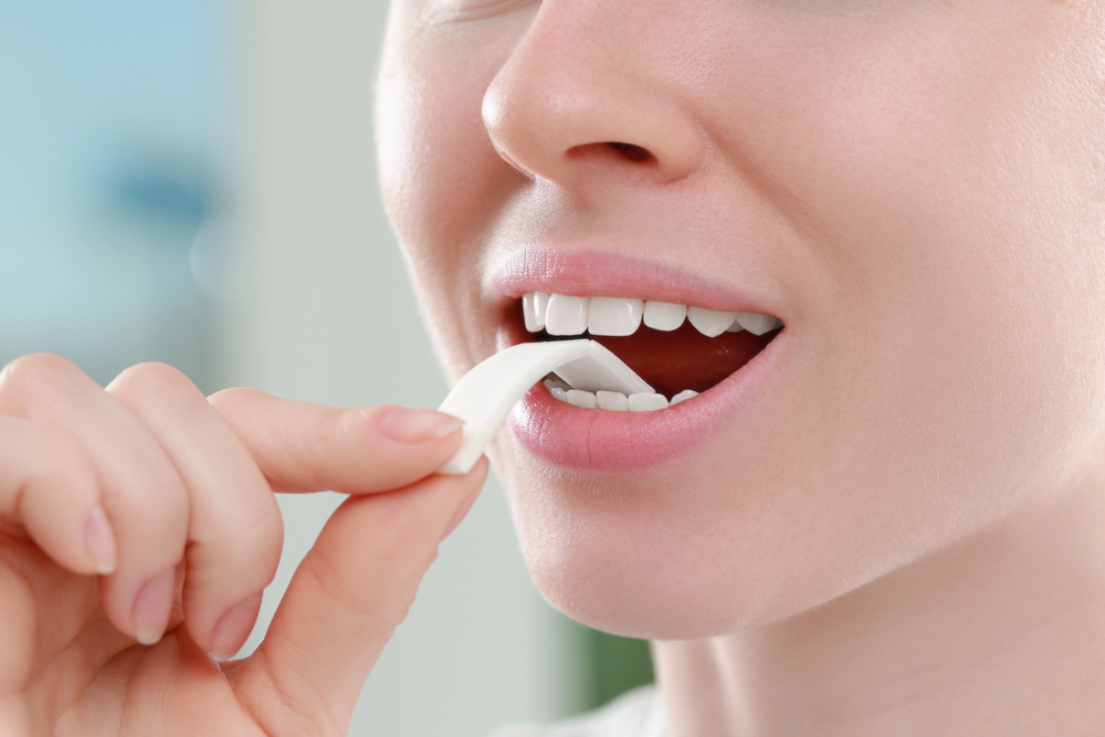 close up of placing a piece of gum in her mouth